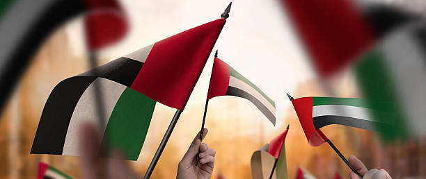 istock Arab Emirates flags in their hands on a blurred urban background 2243723733