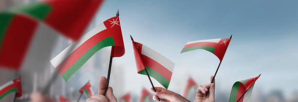 istock Oman flags in their hands on a blurred urban background 2243724067