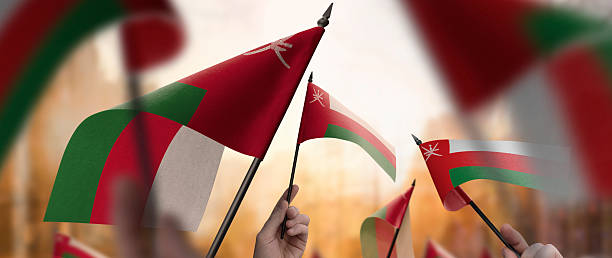 istock Oman flags in their hands on a blurred urban background 2243724070