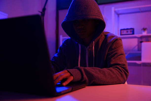 istock A mysterious hooded hacker working on a computer in a dark room. 2243725218