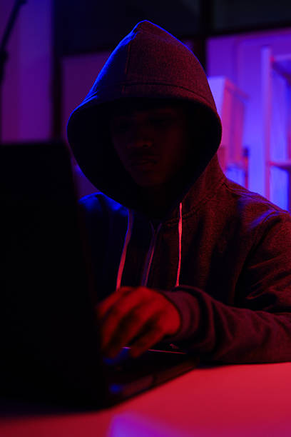 istock A mysterious hooded hacker working on a computer in a dark room. 2243725223