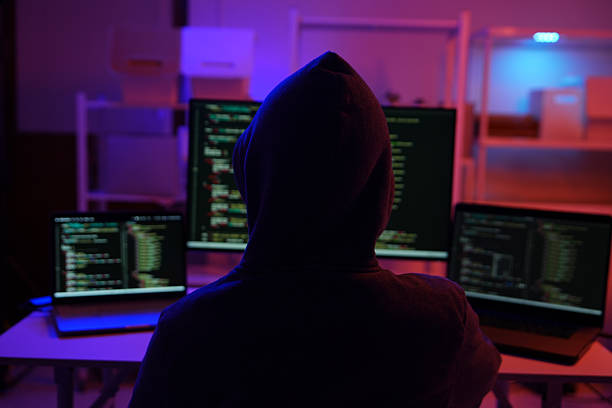 istock A mysterious hooded hacker working on a computer in a dark room. 2243725228