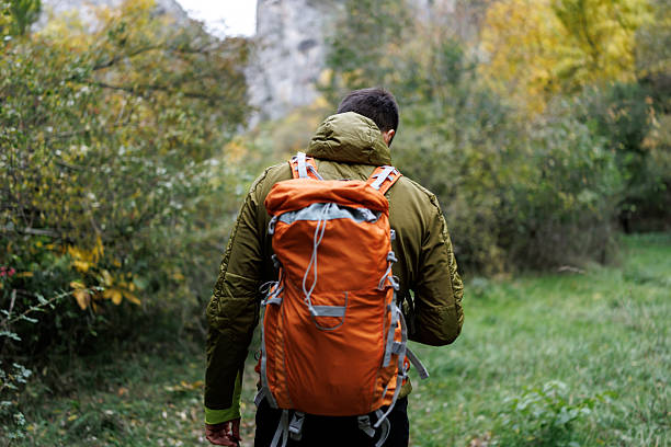 Man with backpack hiking alone in beautiful autumn nature