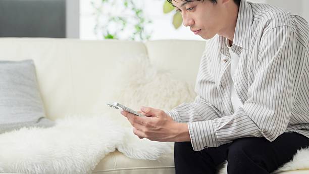 istock Asian man looking at smartphone in living room 2243727255
