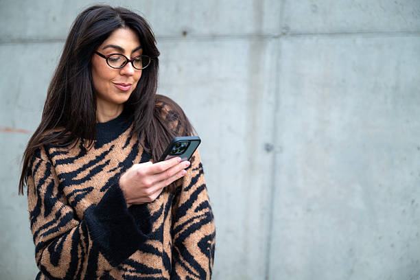 istock Beautiful young smiling woman using her phone outdoor 2243729021