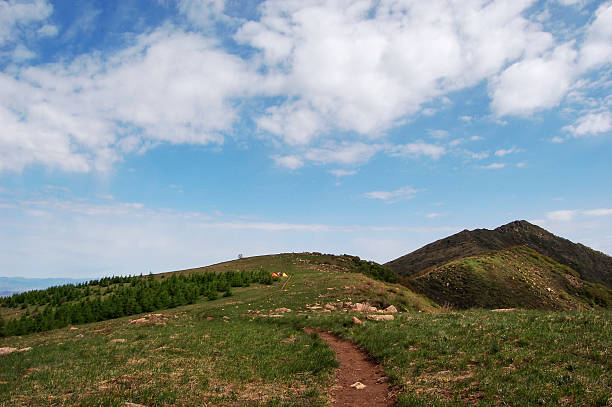 A beautiful outdoor landscape featuring green grass, a clear blue sky with clouds, and rolling hills.
