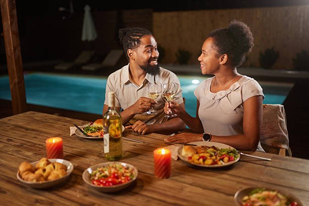 istock Happy black couple toasting during dinner on a patio by the pool. 2243733391