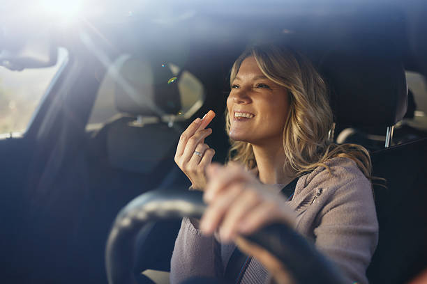 istock Happy woman applying lip gloss in a car. 2243734573