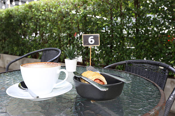 Hot coffee cup and croissant sausage on wooden table in cafe