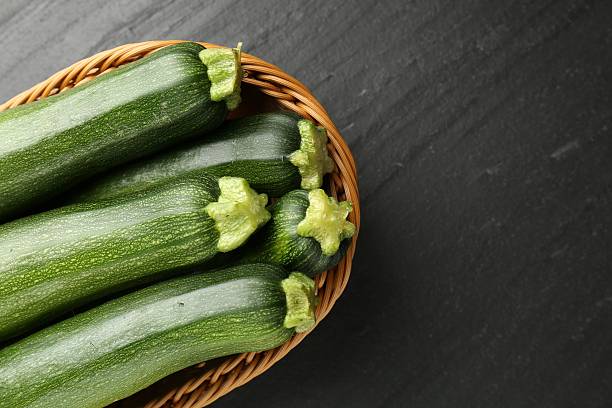 istock Fresh ripe zucchinis in wicker basket on black table, top view. Space for text 2243736074