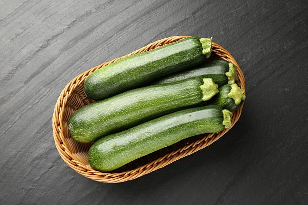 istock Fresh ripe zucchinis in wicker basket on black table, top view 2243736080