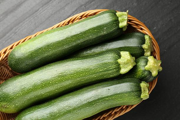 istock Fresh ripe zucchinis in wicker basket on black table, top view 2243736127