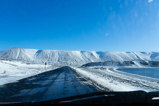 Paved road winding through a snow-covered landscape during a winter road trip in iceland