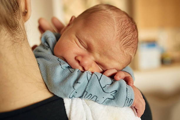 istock Newborn baby sleeping peacefully on parent’s shoulder 2243737738
