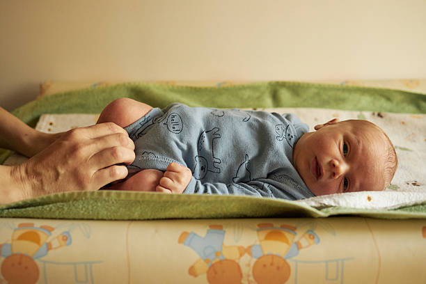 Parent hands dressing infant on a changing table, showing care and bonding