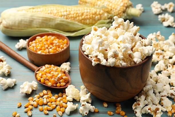 istock Tasty popcorn and corn kernels on blue wooden table, closeup 2243739093