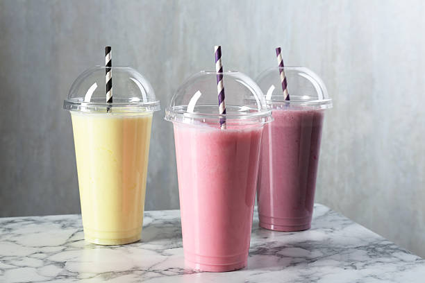 istock Milkshakes of different flavors in plastic cups on white marble table, closeup 2243741896