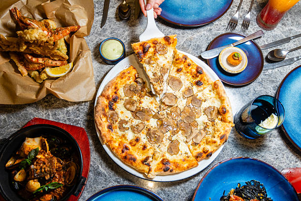 istock Overhead view of gourmet dining table with truffle pizza, seafood 2243743038