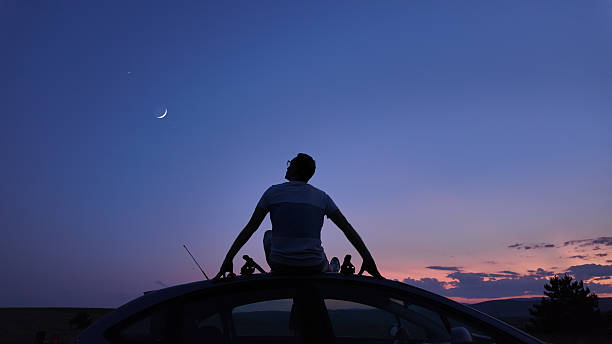 istock Man watching stars, Milky Way, planets, Moon and other celestial objects from a car rooftop from a dark countryside location. 2243743050