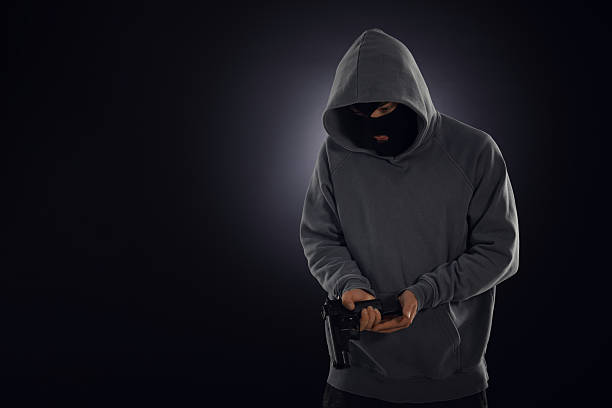 istock Criminal in mask with gun on dark background. Space for text 2243743567