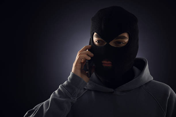 istock Criminal in mask talking on phone against dark background. Space for text 2243743689