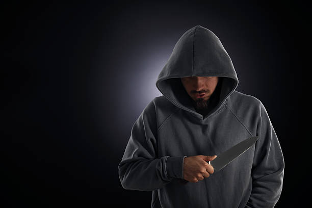 istock Criminal in hood with knife on dark background. Space for text 2243743817