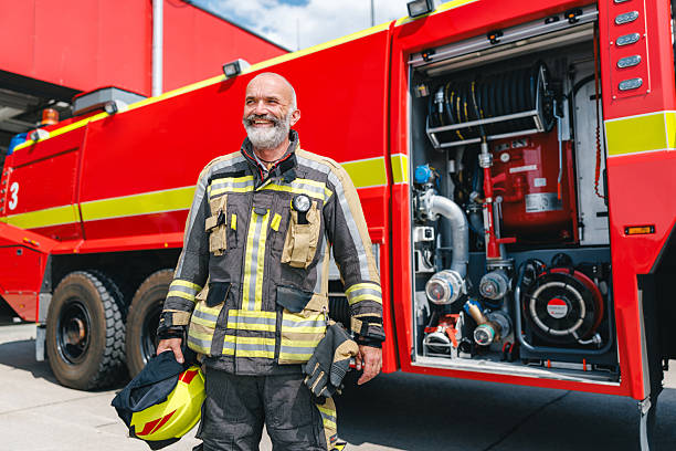 istock Joyful Mature Caucasian Firefighter Standing Confidently by Fire Engine in Bright Daylight 2243744448