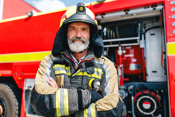 istock Determined Mature Caucasian Firefighter Standing Firmly Beside Fire Engine in Bright Daylight 2243744449