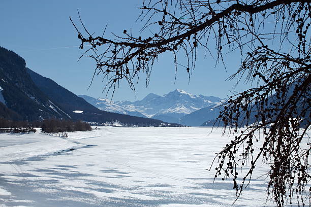 istock Snow-Covered Alpine Mountains Framed by Pine Trees Over a Frozen Lake 2243746198