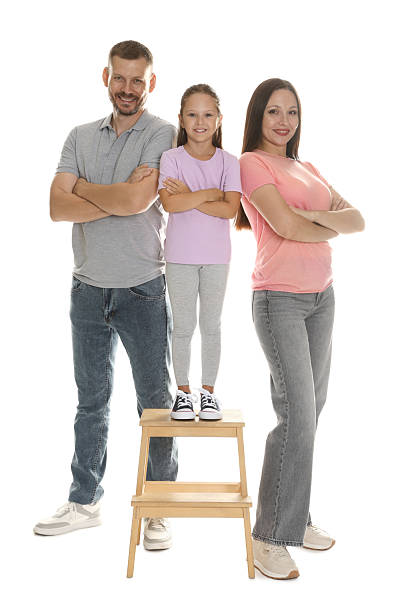Family portrait of mother, father and teenage children. Caucasian and stylishly dressed family smiling and looking at camera against white background.