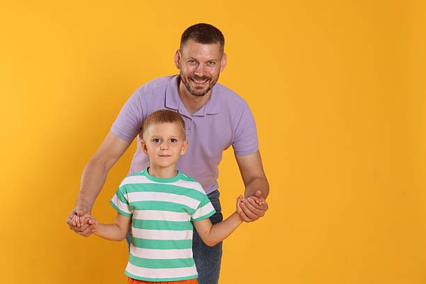 istock Happy father and son on yellow background. Space for text 2243747617