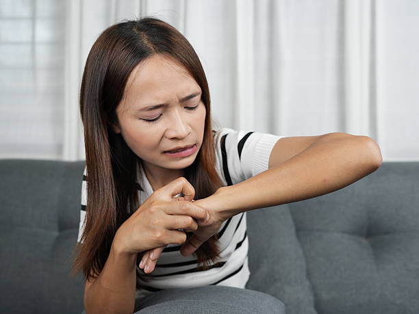 istock Young woman experiencing discomfort while scratching her wrist at home on a comfortable couch in a bright living room setting with natural light 2243747951