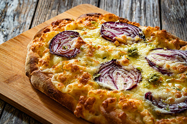 Pinsa with mozzarella cheese and spanish onion on wooden background