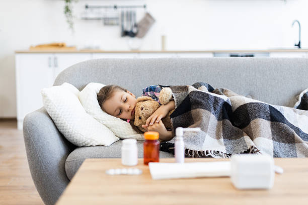 istock Sick child resting on a couch with a teddy bear 2243748855