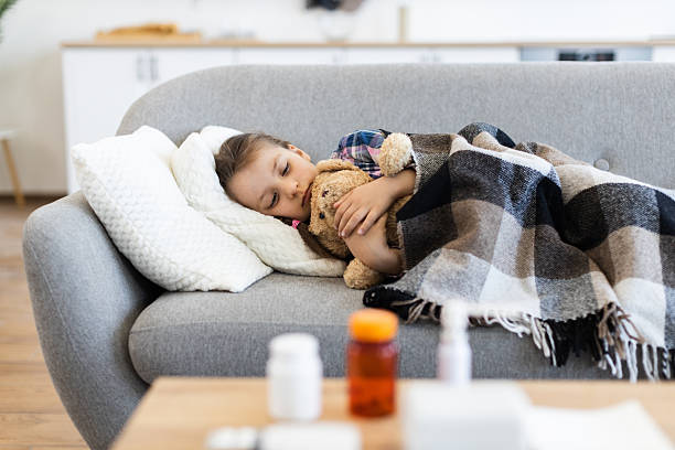 istock Sick child resting on a couch with a teddy bear 2243748863