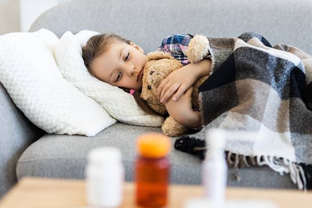 istock Sick child resting on a couch with a teddy bear 2243748866