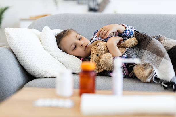 istock Sick child with a thermometer resting on the couch 2243748868