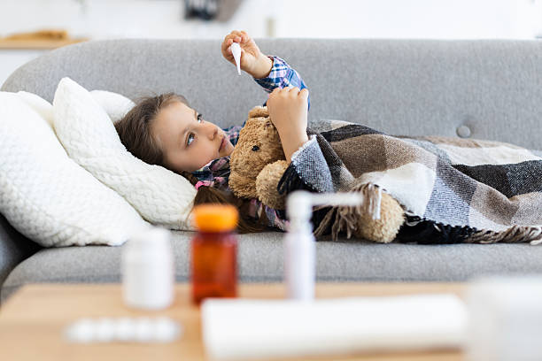istock Sick child with a thermometer resting on a couch 2243748874