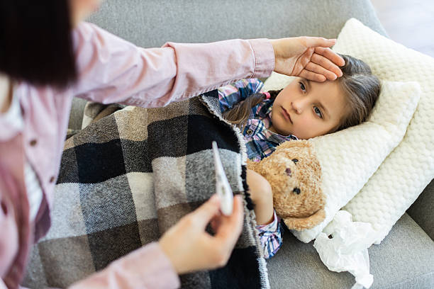 istock Sick child with a fever being cared for at home 2243748952
