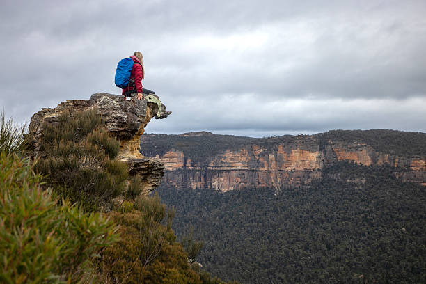 istock Female hiker sits high up on a rock precipice overlooking mountains 2243752997