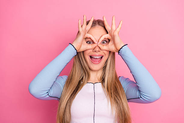 istock Cheerful young woman with a playful pose and bright expression against a vibrant pink background in casual fashion. 2243753049