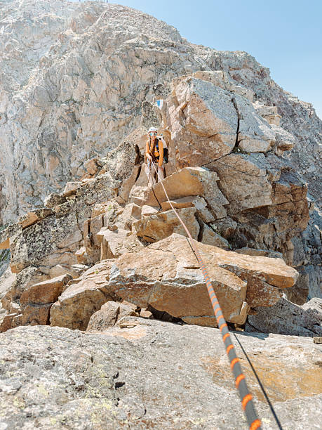A man helps a friend climb to the top of a boulder