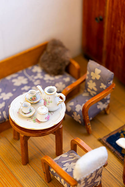 Miniature tea set with floral pattern on a small table in a dollhouse setting