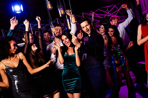 istock Energetic party night crowd dances under neon lights with friends smiling while DJ plays music and guests celebrate together at the club 2243756692