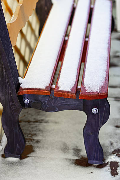Wooden bench covered in fresh snow stands outdoors in winter park. Symbolizes cold season, chill, tranquility and empty relaxation spot. Perfect for nature, frosty weather and solitude concepts.