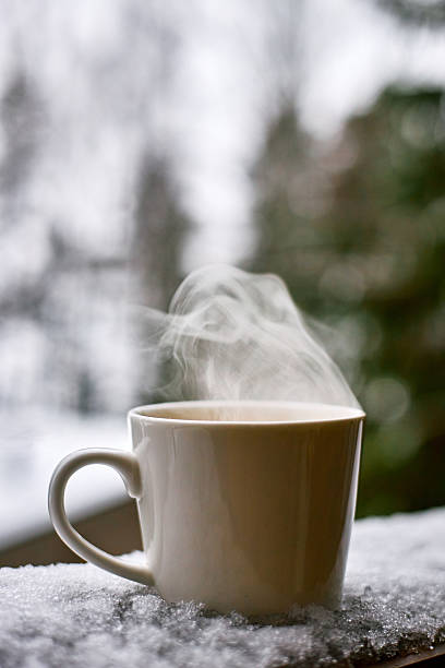 Hot Coffee Cup Emitting Steam Outdoors during Winter Morning on Snowy Surface
