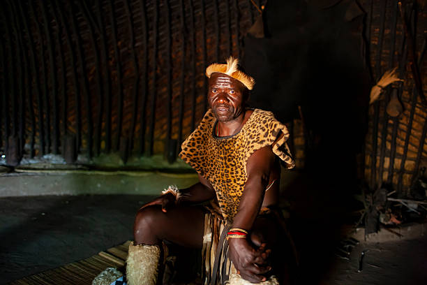 portrait headshot of single african man with eye deformity. in the village with dreadlocks in front of his home with thatched roof