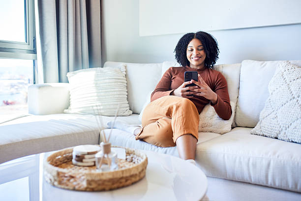 istock Happy Black Woman Smiling While Relaxing and Texting on Sofa 2243763308