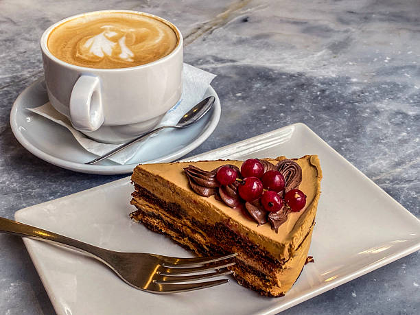 High angle close-up view of a chocolate cake slice with coffee and milk served at sidewalk cafe