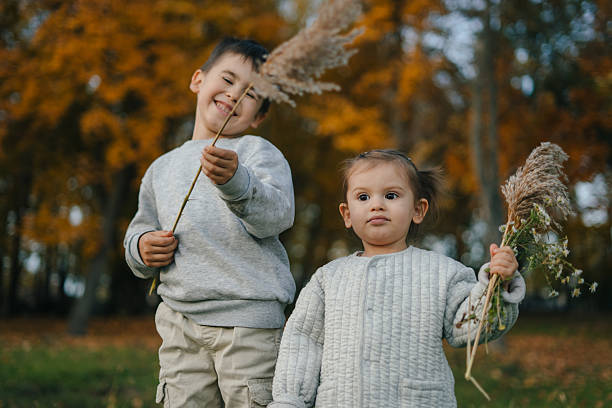 Young siblings enjoying open field with pampas grass blooms